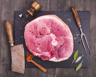 uncured pork ham steak with knife on cutting board