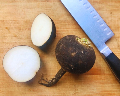 organic black radish on a cutting board with knife