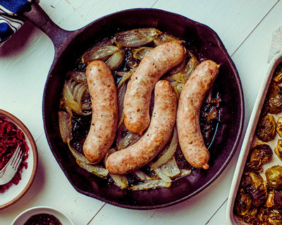 jacuterie's bratwurst in a cast iron skillet with onions